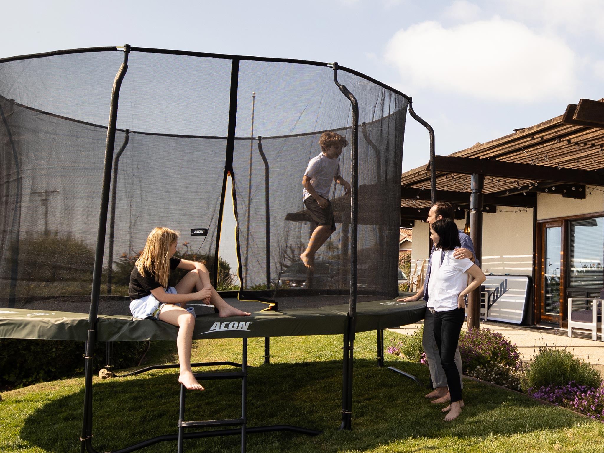 Familjen tittar på barn som hoppar på en trampolin