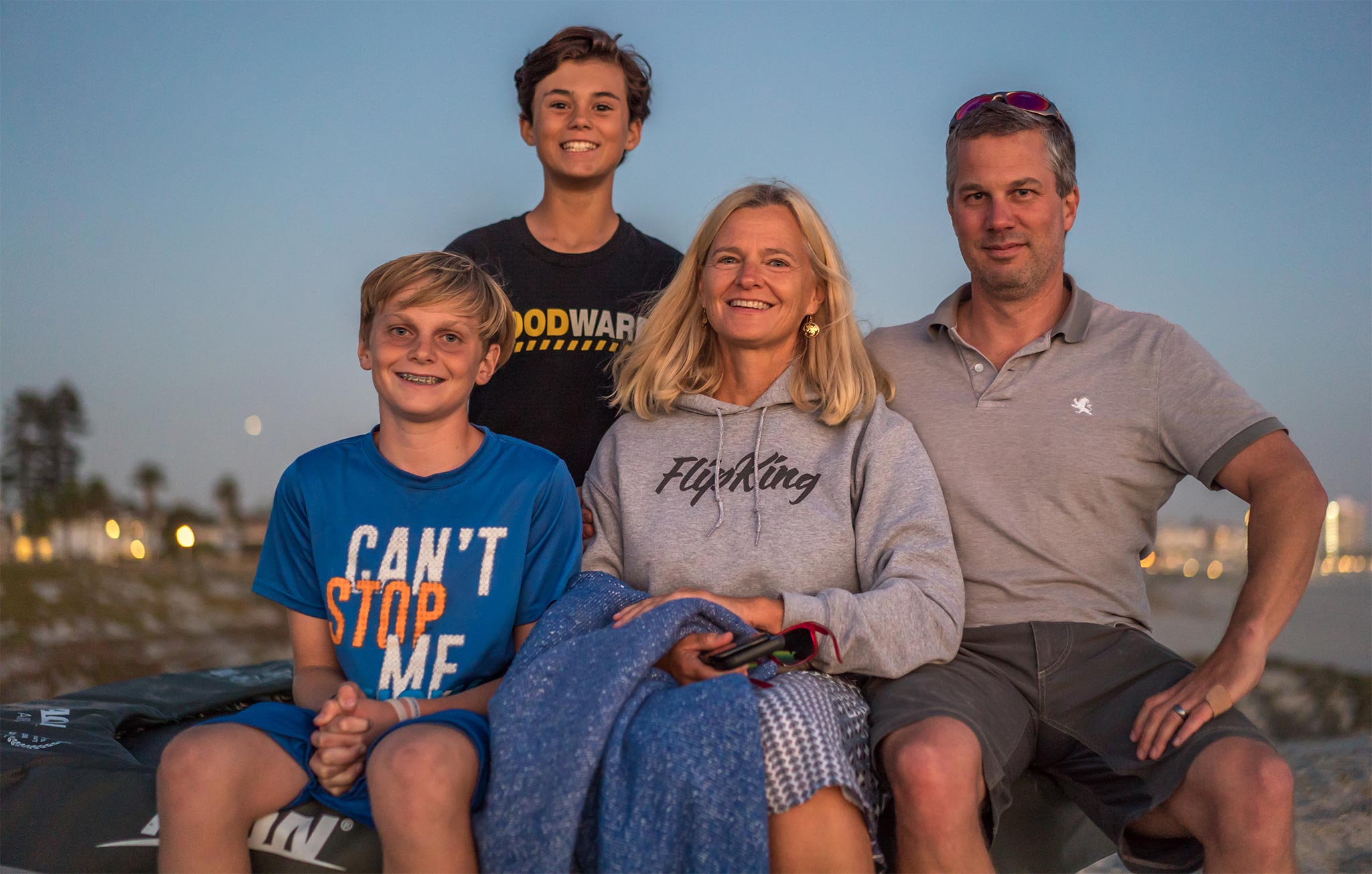 Acon-kundfamilj med mamma och tre pojkar som sitter på stranden