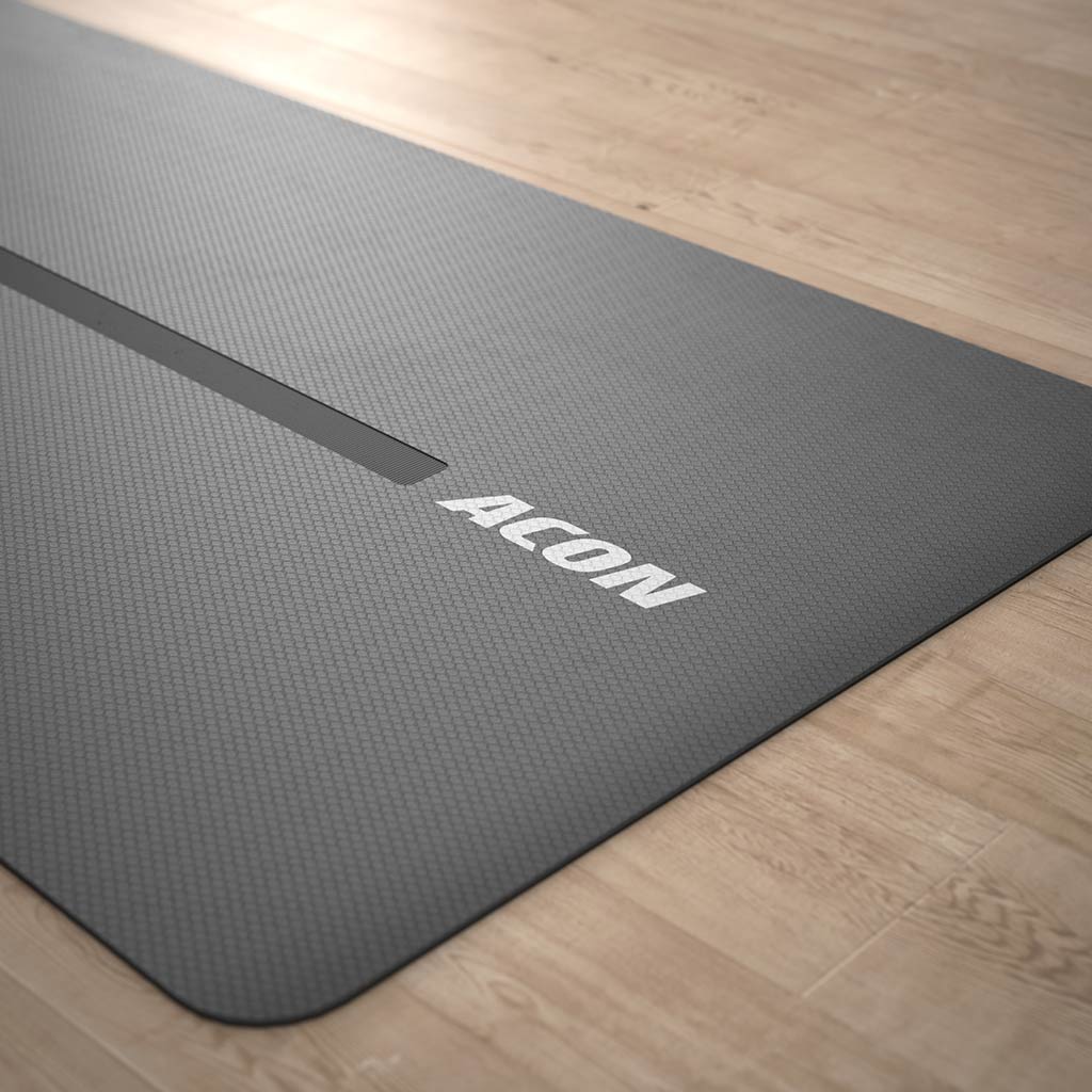 Image of Acon Eco-friendly Yoga Mat partially rolled up, lying on a wood yoga studio floor.