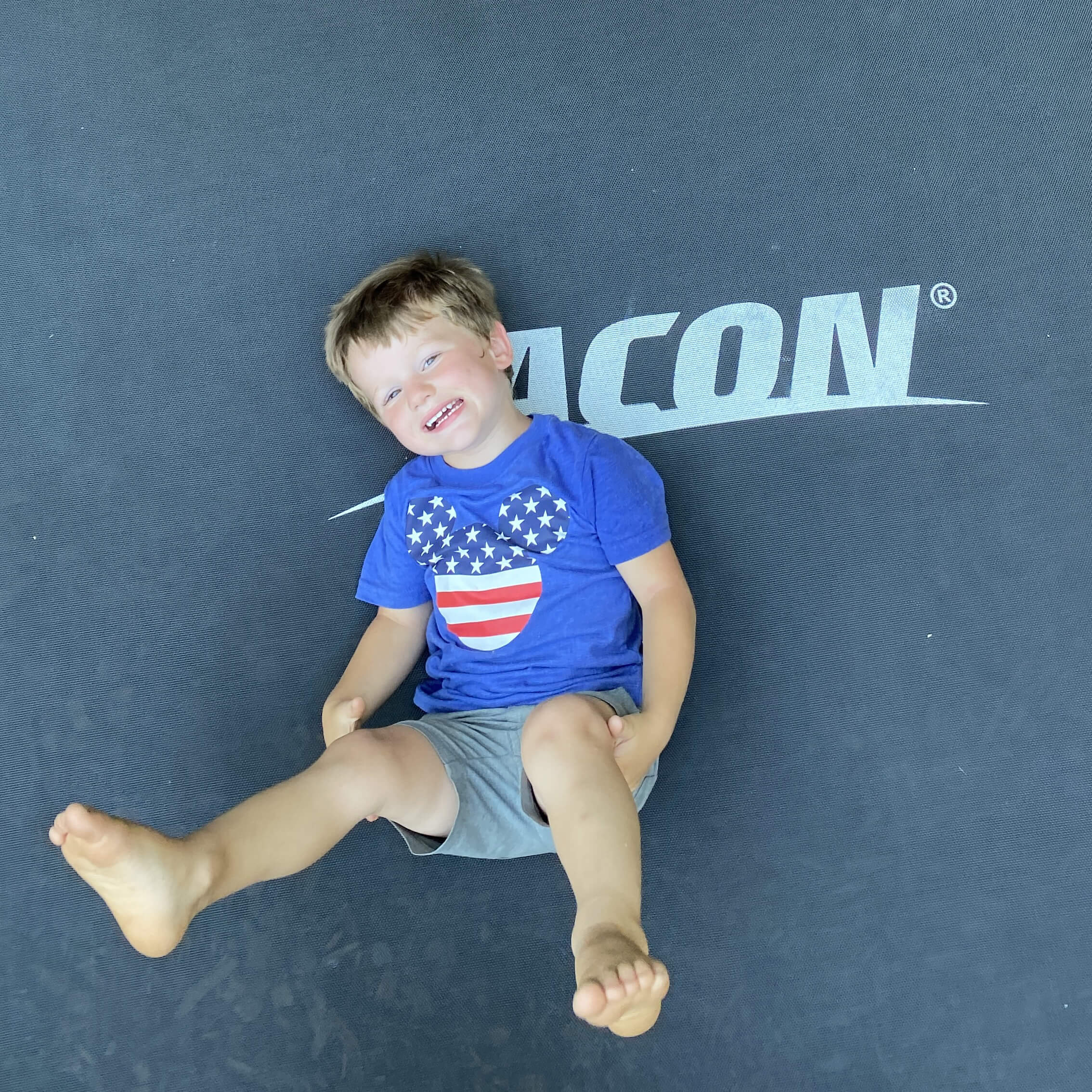En glad pojke som ligger på en Acon studsmatta.