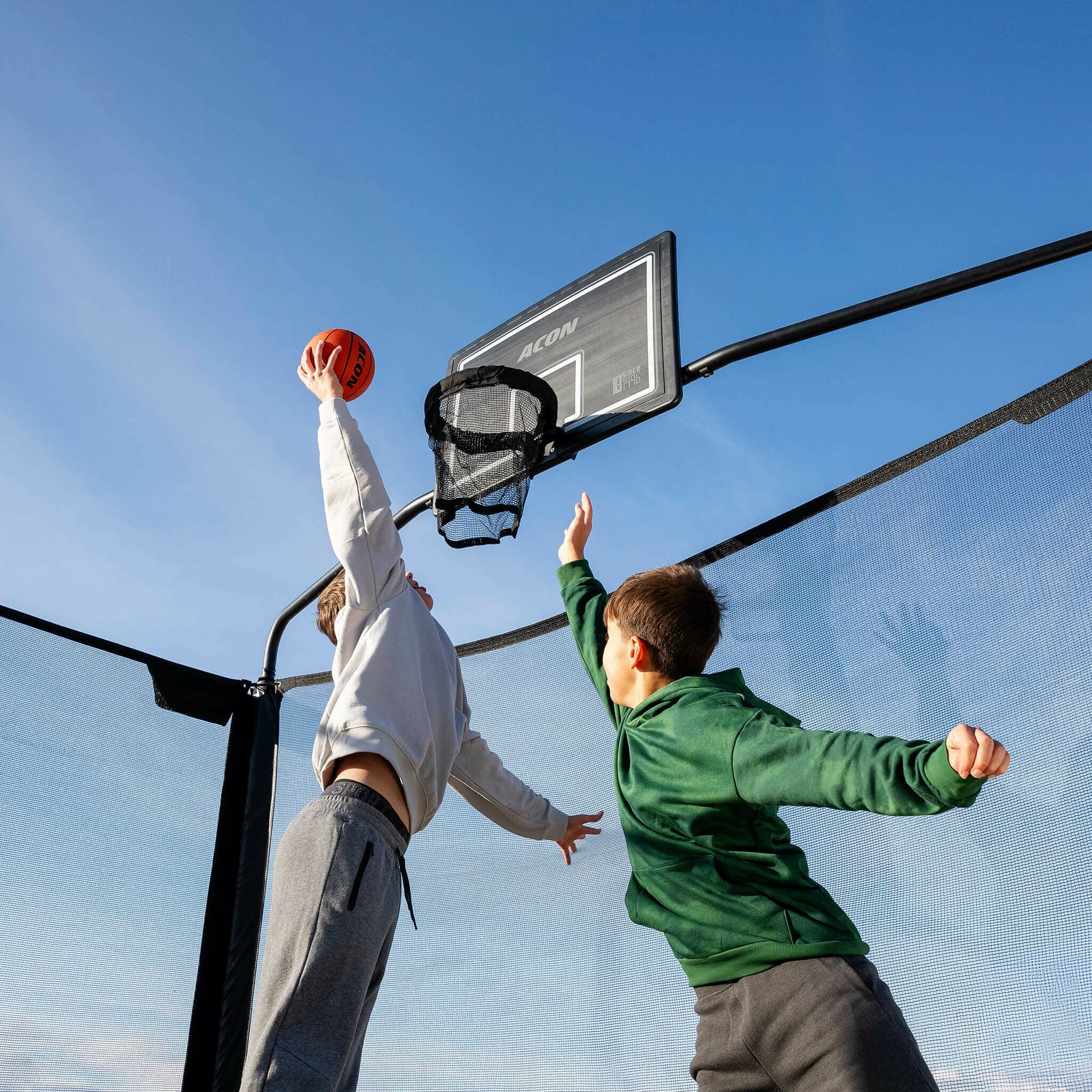 Två pojkar spelar basket på Acon X studsmatta.