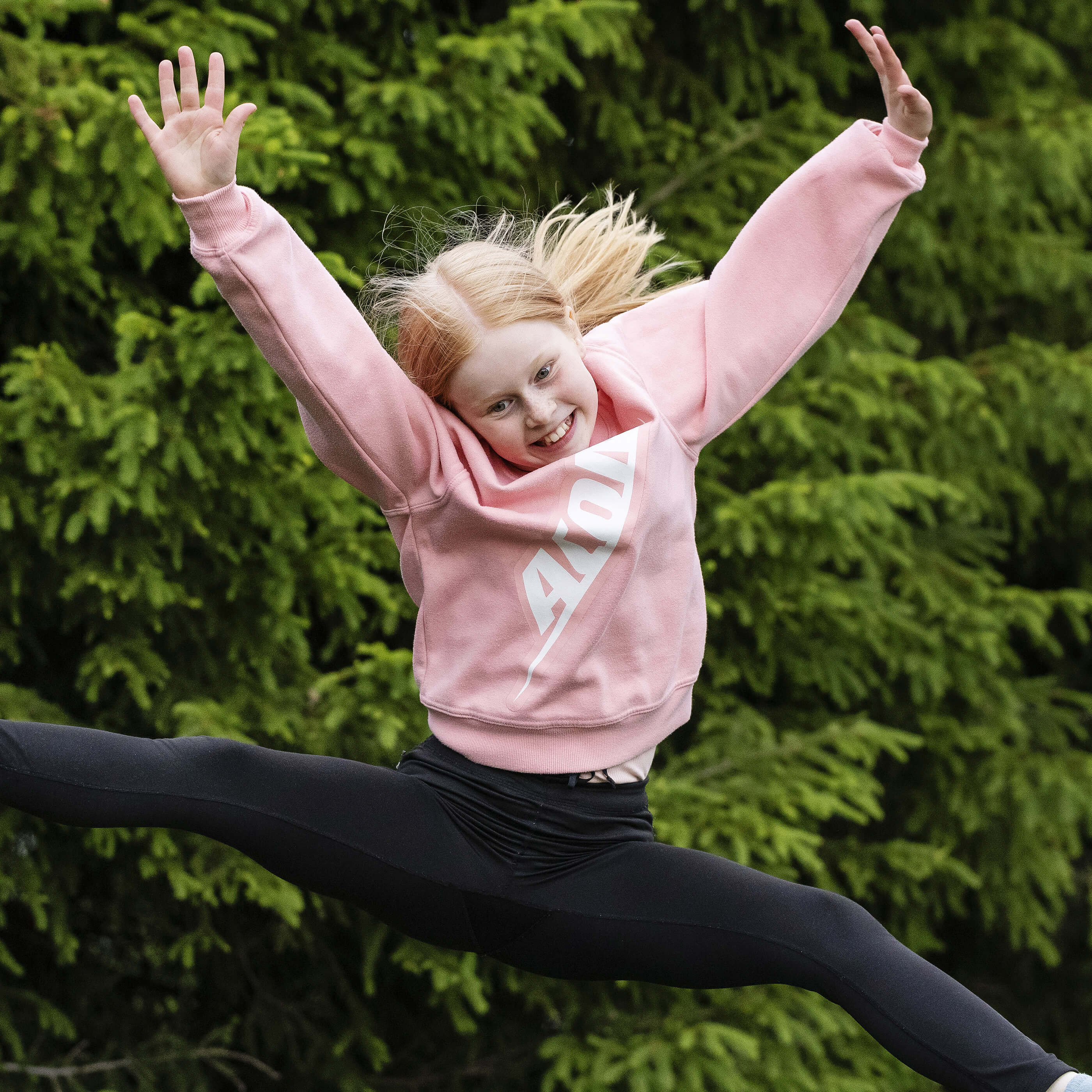 En glad tjej i en Acon-tröja hoppar på en studsmatta.