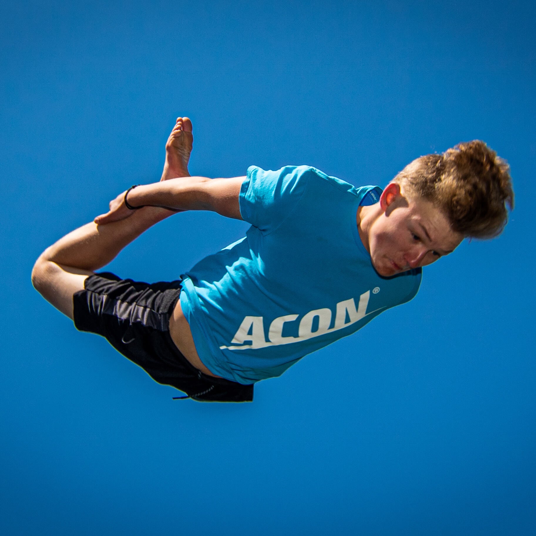 En pojke i en blå acon t-shirt hoppar studsmatta.