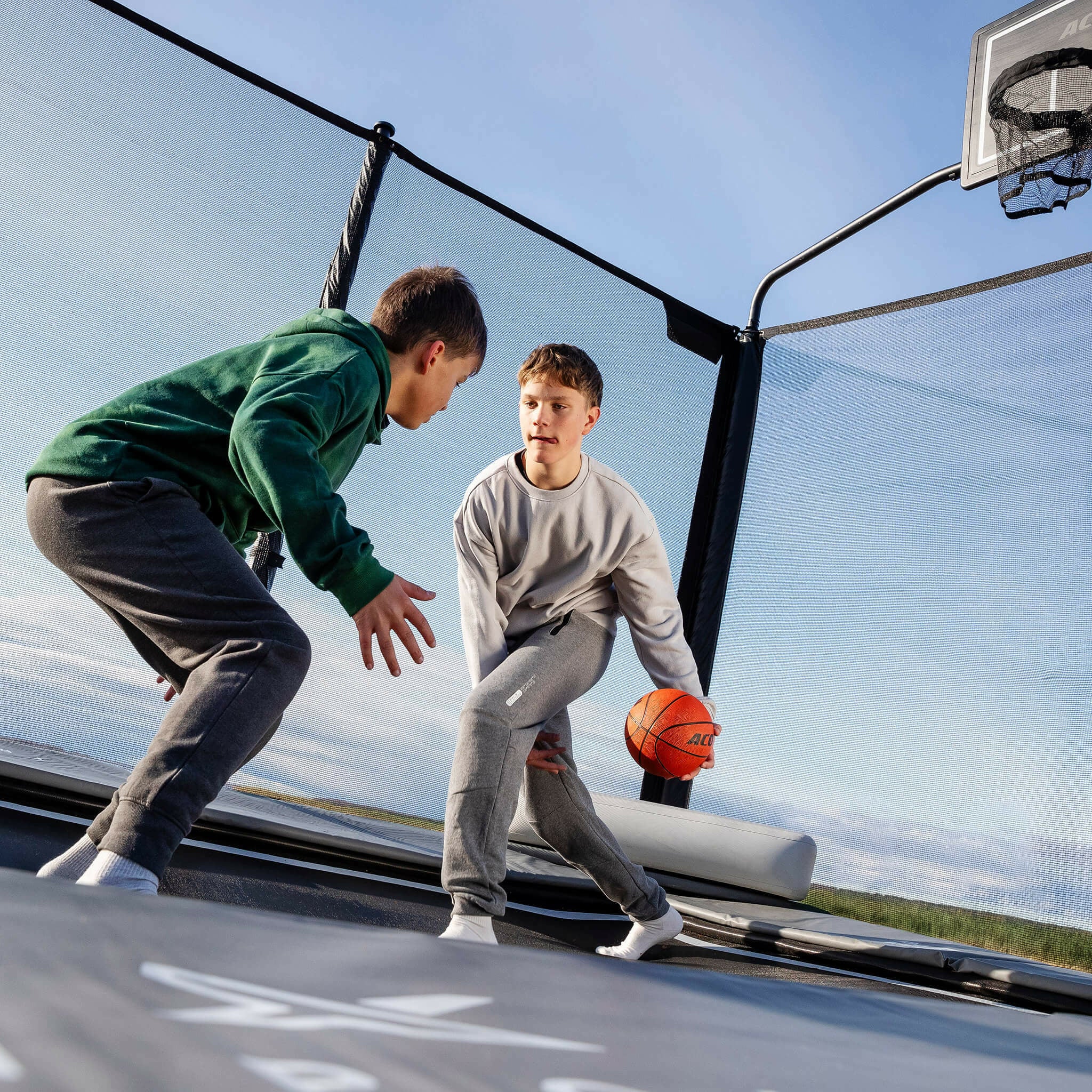 Två pojkar spelar basket på Acon X studsmatta.
