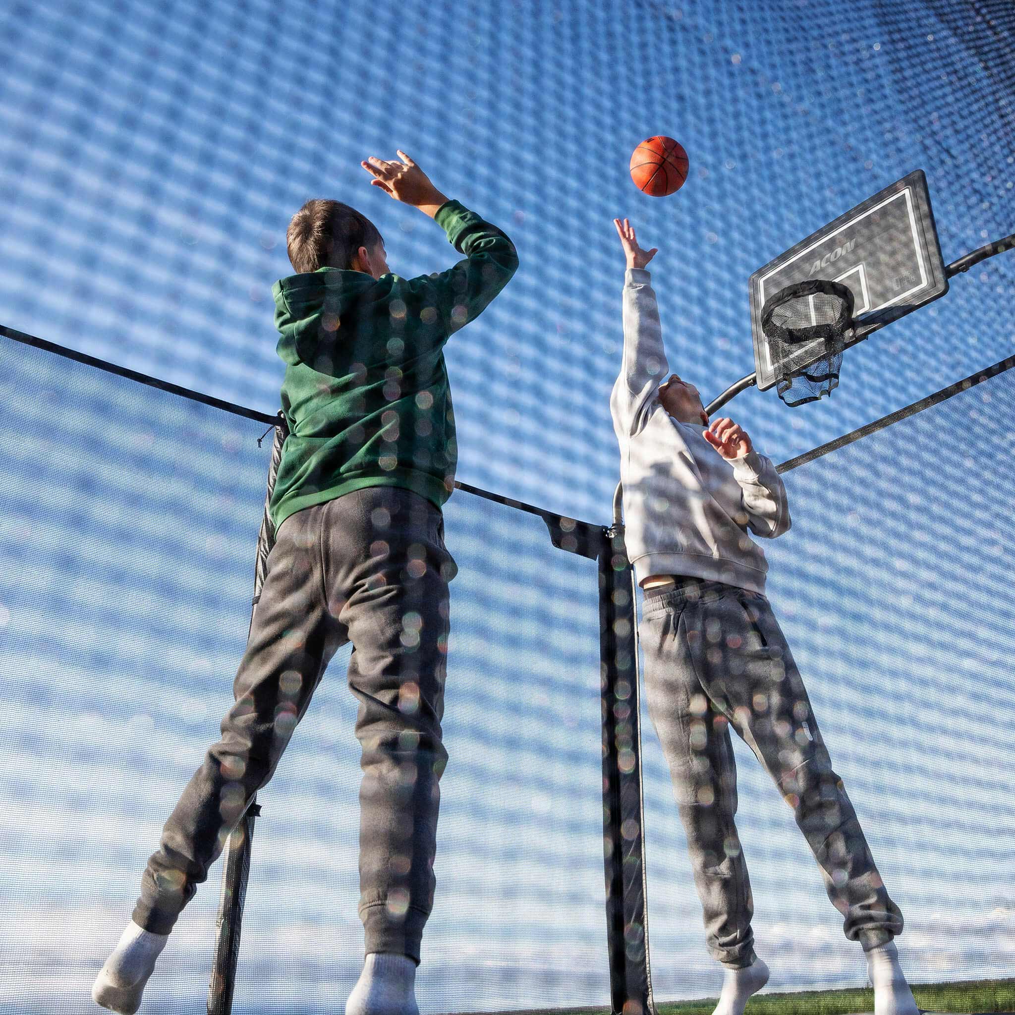 Två pojkar spelar basket på Acon X studsmattan.