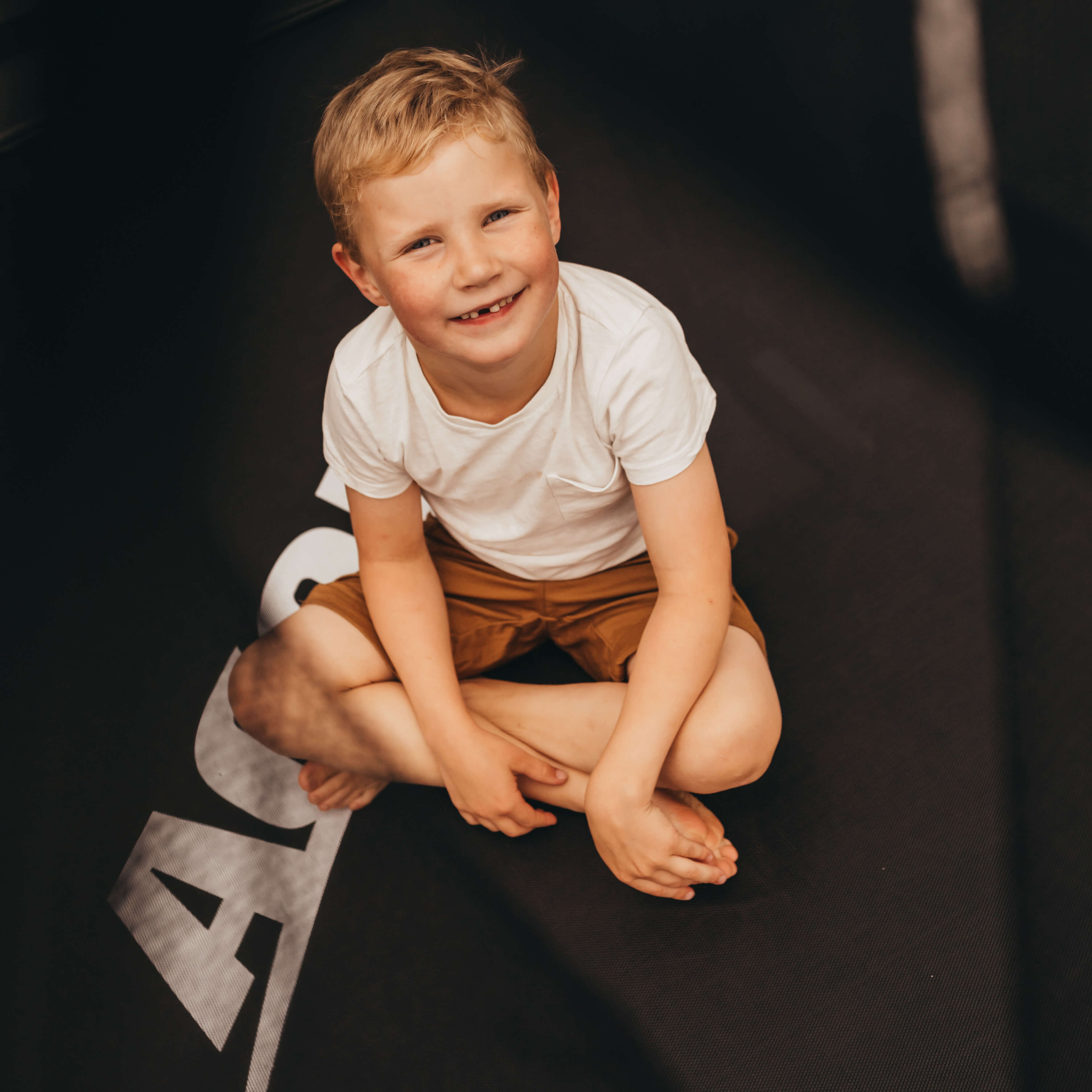 En skrattande pojke sitter på en Acon studsmatta.