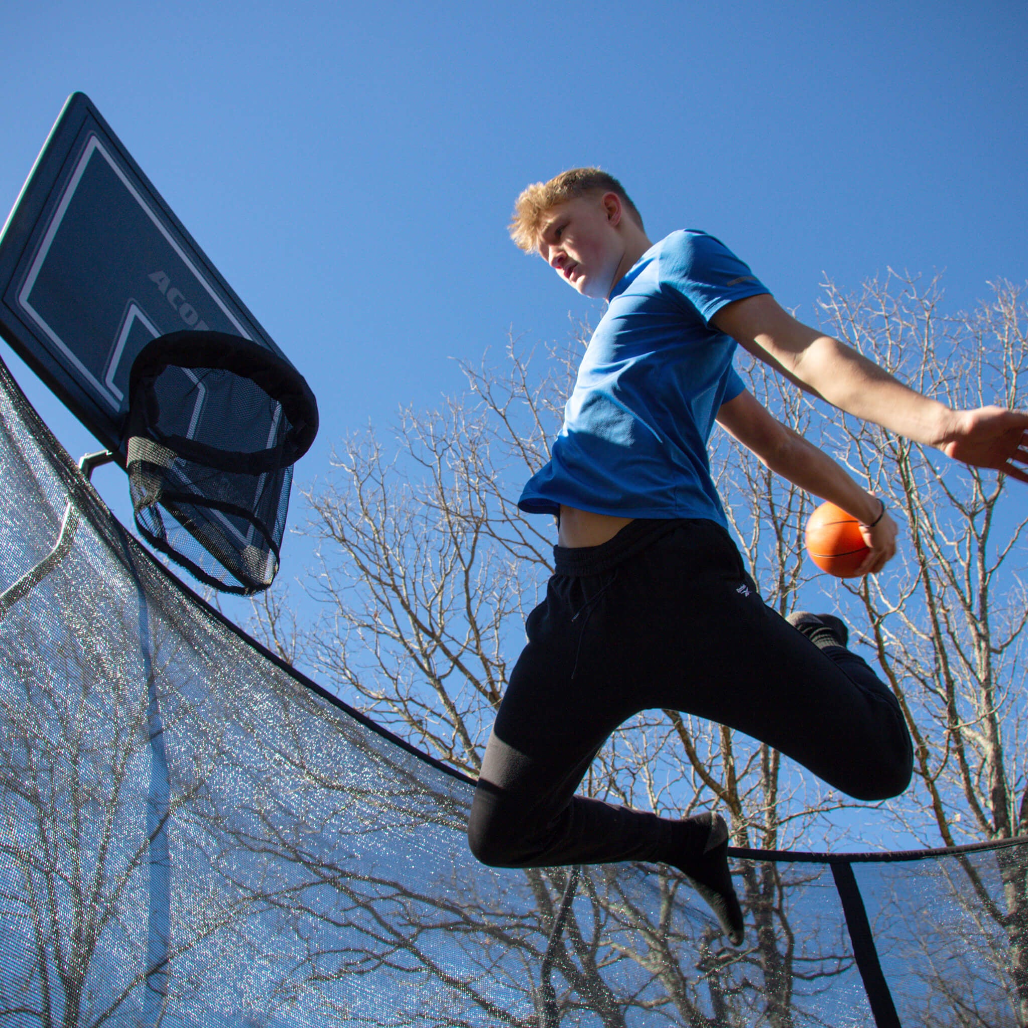 En pojke spelar basket på studsmatta.
